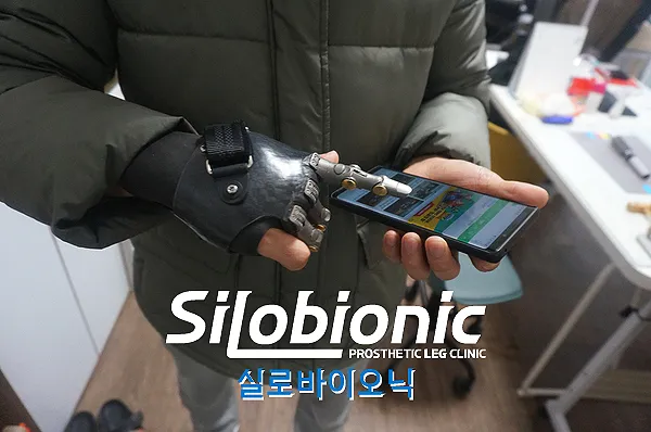 티타늄 반자동 의수를 끼고 휴대전화를 든 모습