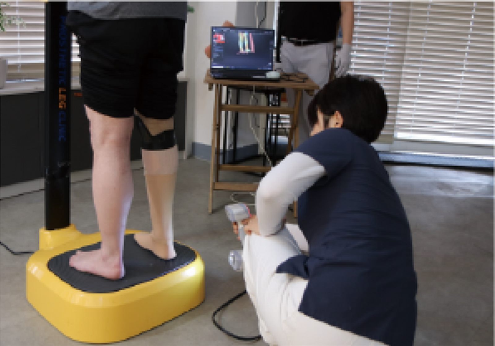 하퇴 의족을 신고 3D 스캐너 발판 위에 선 고객님과 다리를 측정하는 전문가