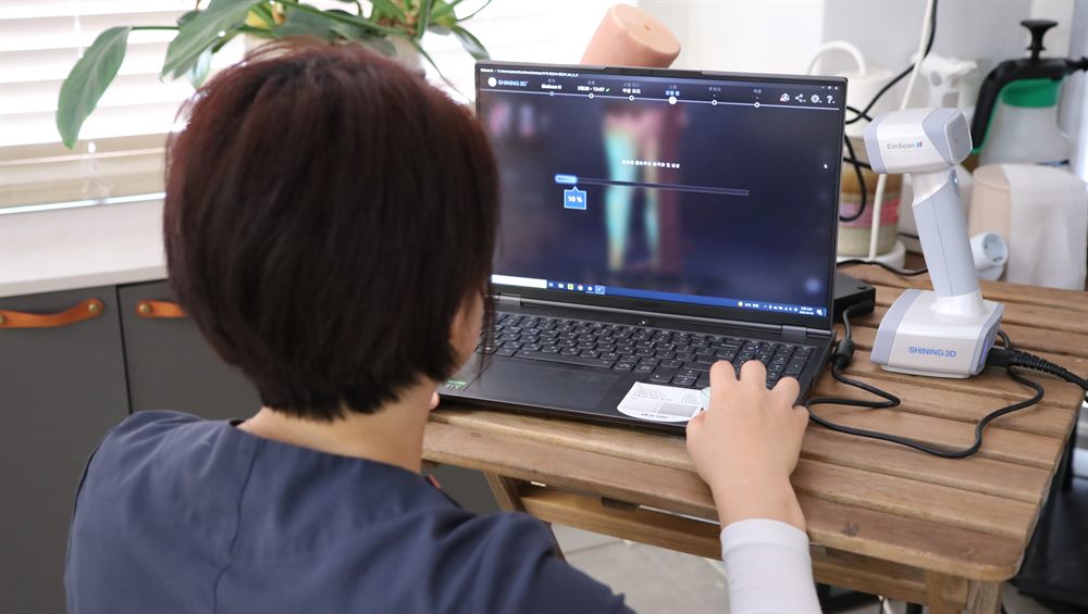 휴대용 3D 스캐너로 측정한 다리 데이터를 노트북에서 확인하는 전문가