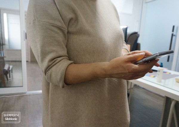 الإمساك بهاتف محمول مع ارتداء طرف صناعي للساعد من السيليكون