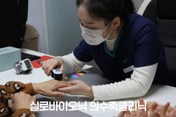 E-SKINスキャナーでお客様の手の肌の色を測定するスタッフ